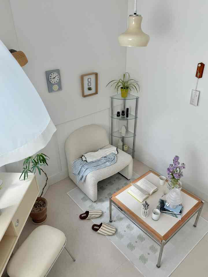 A small study space in ivory and white tones featuring an armchair and coffee table with neat and simple decor