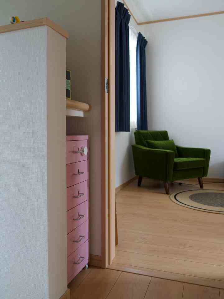Natural color and blue curtains in a small bedroom entrance, featuring a green armchair and pink cabinet creating a cozy atmosphere