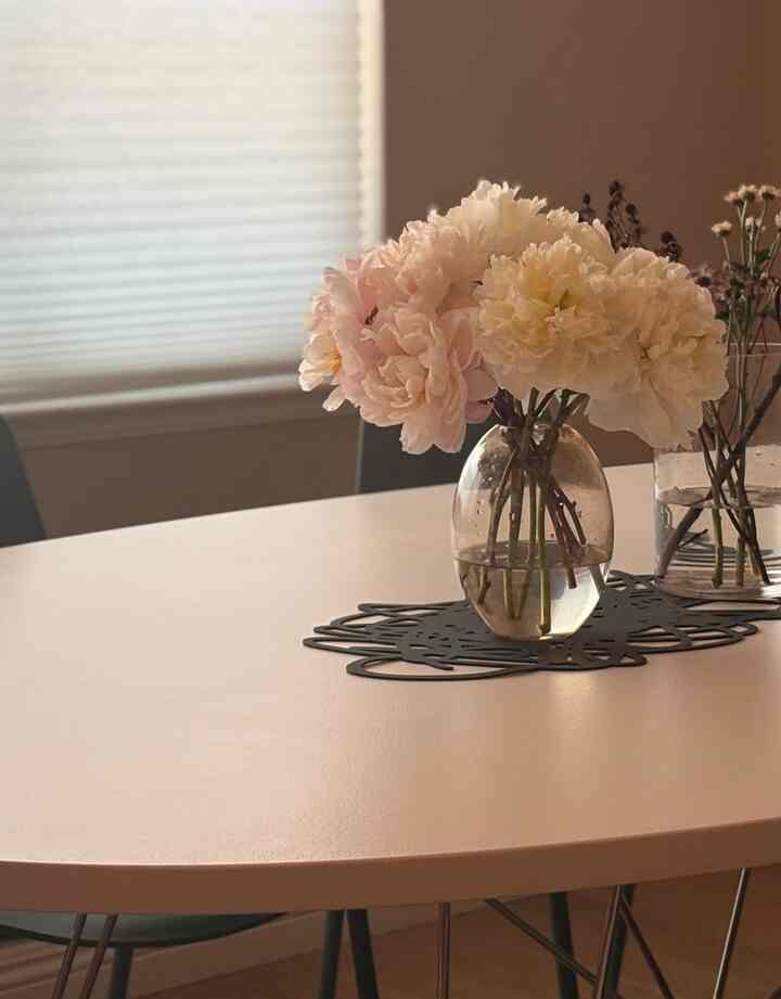 Warm beige-toned dining room featuring vases with flowers and a placemat on a cozy table