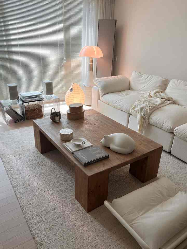 白とナチュラルカラーが調和したリビング、ソファと木製のコーヒーテーブルが落ち着いた雰囲気を演出