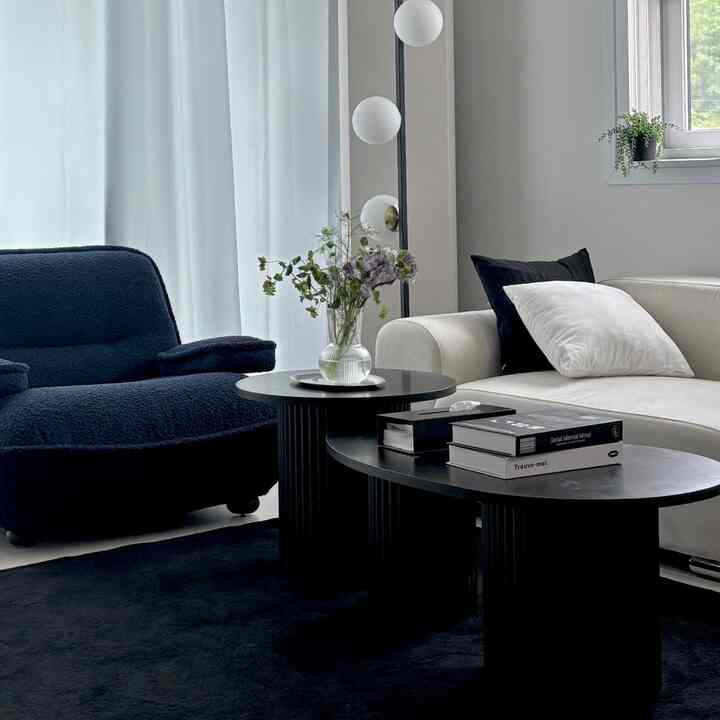 ホワイトとネイビートーンのモダンなリビングルーム、ソファと丸いコーヒーテーブルが配置された落ち着いた空間