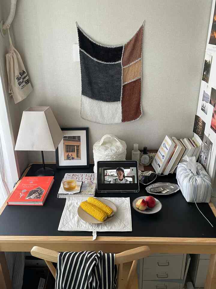Natural vintage study desk with brown wood and black top, featuring white lamp, books, photo frame, and summer fruits in cozy setting
