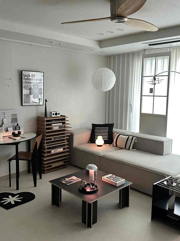 Gray and black monotone living room featuring an L-shaped sofa and black coffee table with a simple, moody ambiance