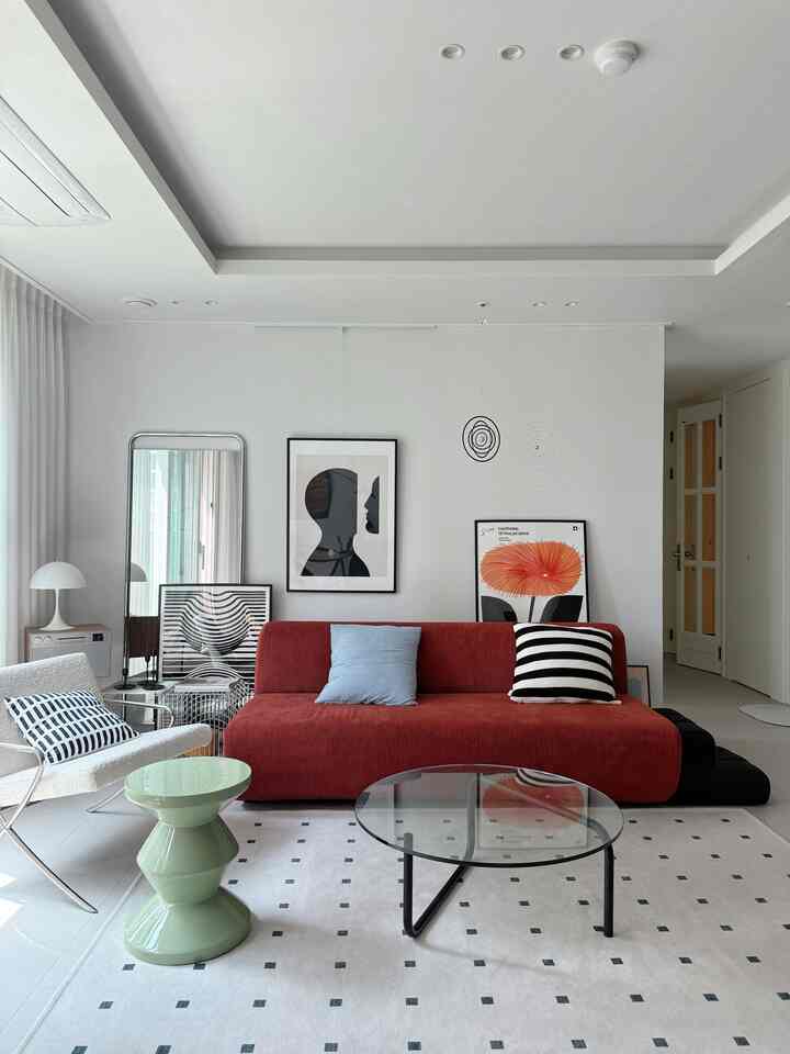 ホワイトトーンのリビング、赤いソファとアートポスターが配置されたモダンなインテリア