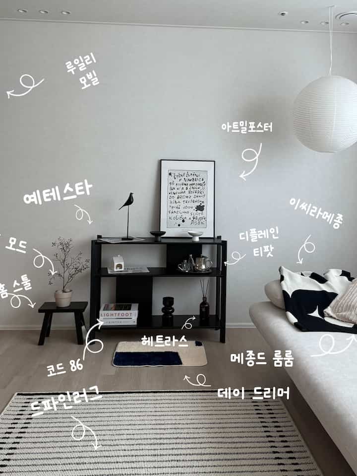 Modern living room with white walls and cream sofa, featuring a black YETESTA shelf and art poster centrally placed, complemented by natural decor