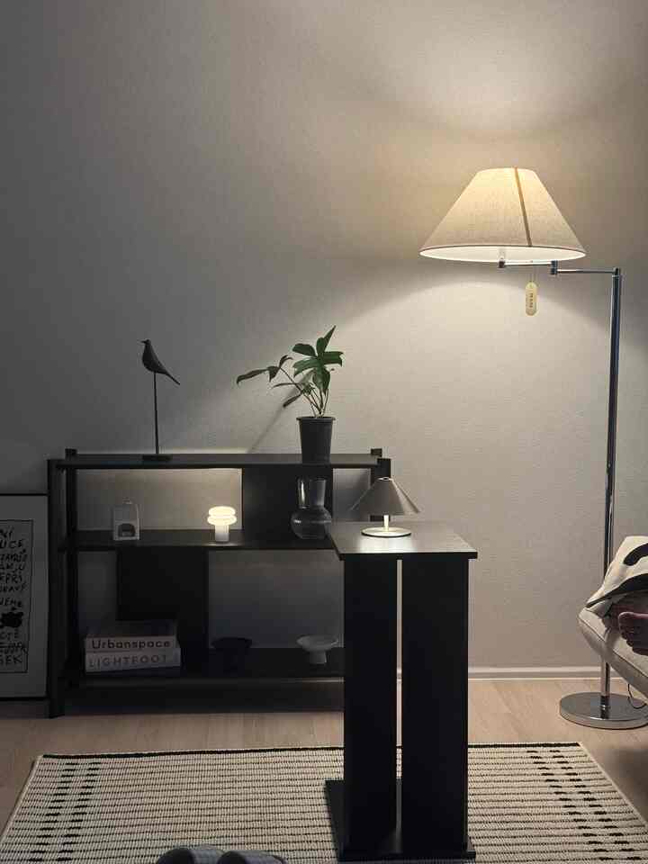 Living room with light wood flooring, black furniture, and warm lighting featuring a simple modern style