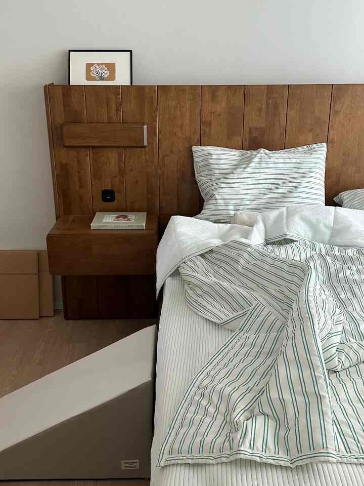 White and wood tone bedroom featuring a wooden bed frame and striped summer bedding, creating a cozy atmosphere
