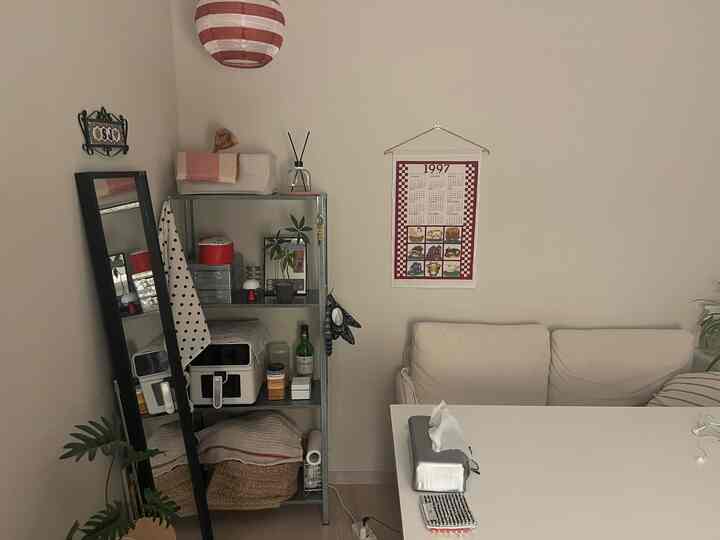 白を基調としたリビング、クリーム色のソファとメタルの棚が配置されたシンプルでナチュラルなインテリア