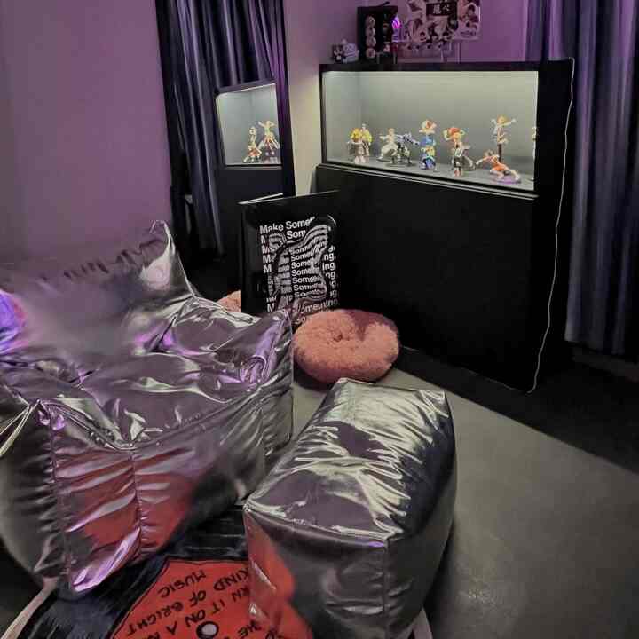 シルバーのビーズクッションソファとLED照明付きフィギュア飾り棚がある暗めの趣味の部屋