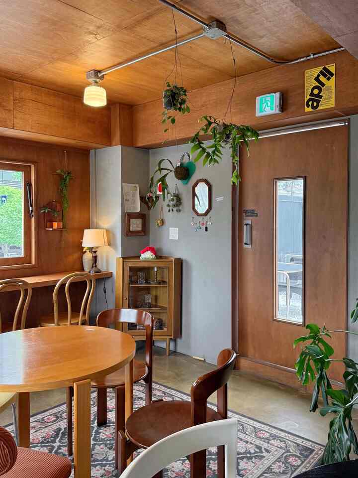 木目調のダイニングルーム、木製のテーブルと椅子、吊り植物が配置された雰囲気のあるヴィンテージカフェ