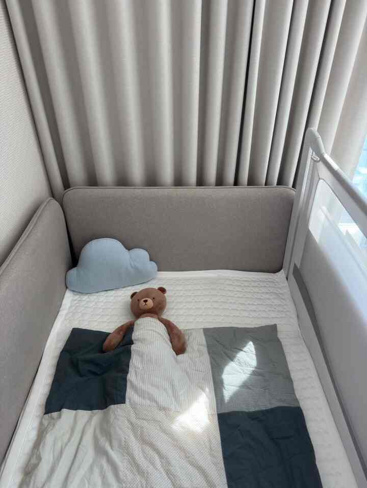 柔らかなグレー調の赤ちゃん用の部屋、安全なベッドガード付きのベビーベッドが配置された、落ち着いた雰囲気のインテリア