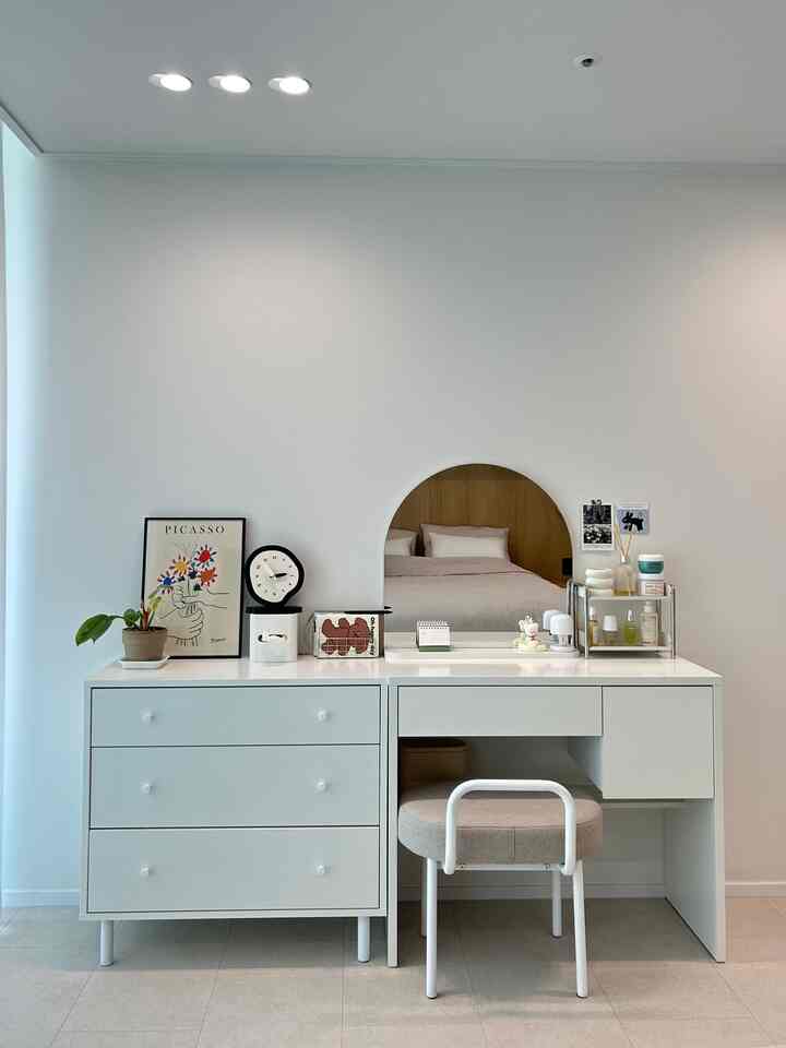 白とナチュラルな色調のパウダールーム、清潔な化粧台と丸い鏡が配置されたシンプルなインテリア