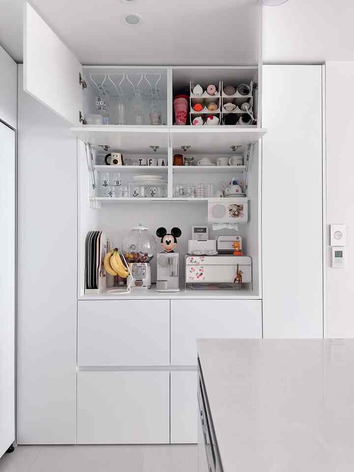 Bright white kitchen space featuring a neat home cafe cabinet with modern minimalistic design