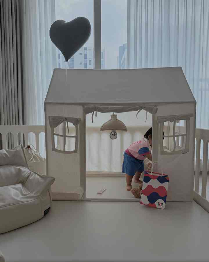 白を基調としたベビールーム、ハートの風船とテント、ビーズクッションが置かれた温かみのある安全な遊び空間