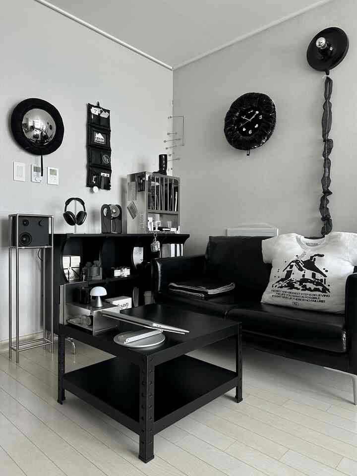 黒と白のモノトーンの書斎兼リビングスペース、黒いソファとコーヒーテーブル、壁時計、本棚が配され、モダンで清潔感のあるインテリア