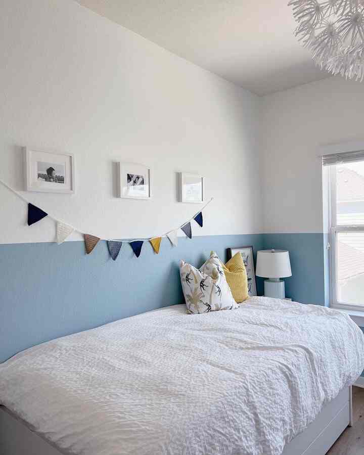 Blue and white toned kids' room featuring a large bed with colorful pillows in a bright and cozy space