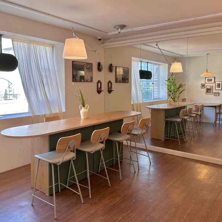 暖かみのある木目調と白色の照明が調和したカフェ風キッチンスペース、長いバーカウンターに椅子が並べられた居心地の良い雰囲気のインテリア