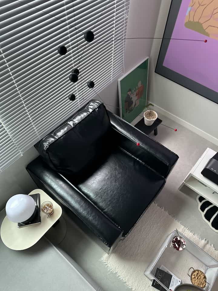 Modern minimal space featuring a black leather single sofa, white floor and walls, and aluminum blinds