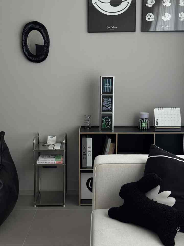 グレーの壁と床のモダンなリビングルーム、ブラックのビーンバッグとベージュのソファが配置された落ち着いた空間