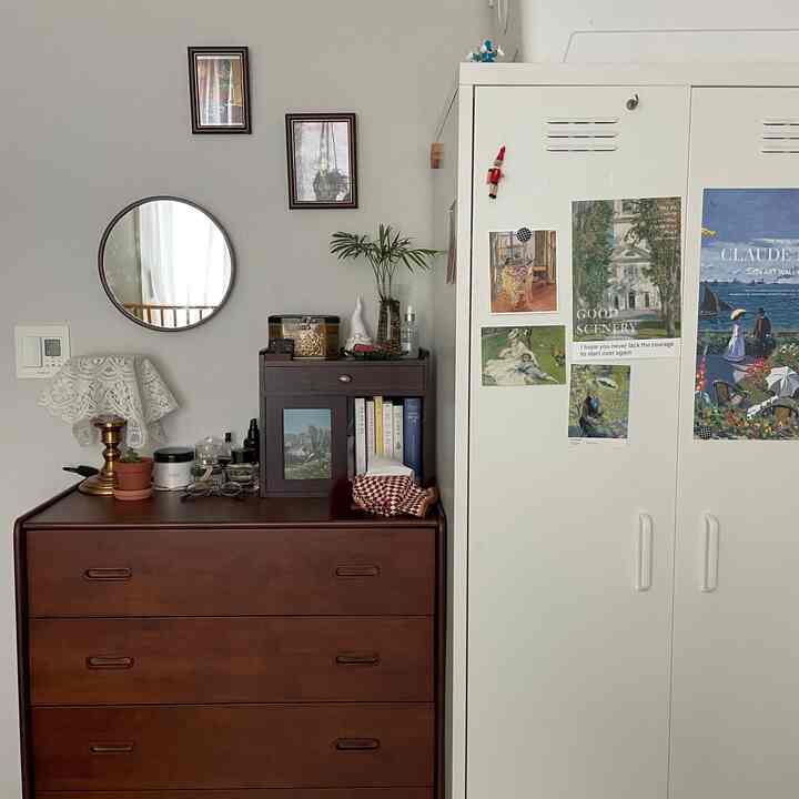 白と茶色のトーンが特徴的な小さな寝室、チェストとワードローブが配置され、温かみのあるナチュラルレトロなインテリア