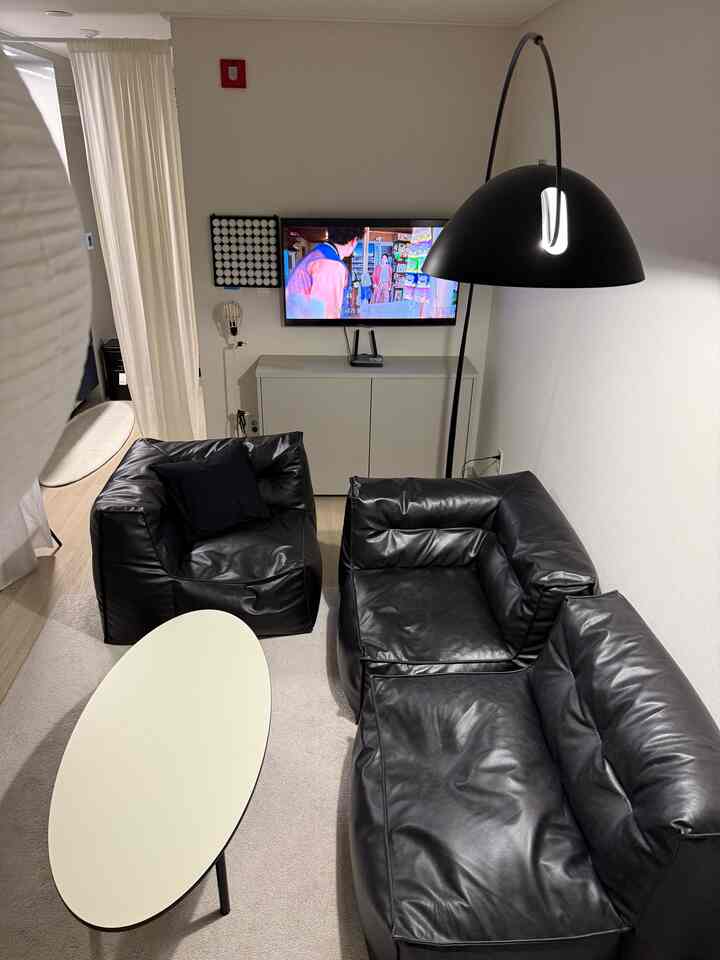 黒いレザーソファと白いオーバルテーブルが配置されたシンプルなワンルームのリビング