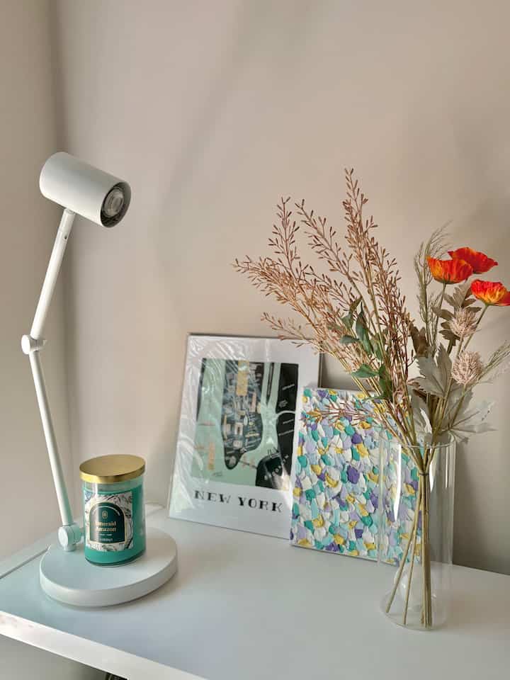 White-toned home office space featuring a clean white desk with white lamp and plants creating a minimal atmosphere