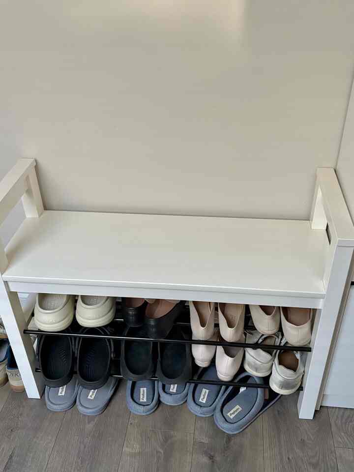 White-toned entrance featuring a clean bench with shoe storage, creating a practical organized space