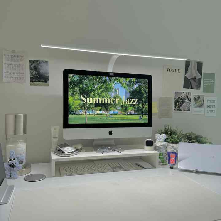 A clean white-toned home office featuring a computer and desk plants in a modern workspace
