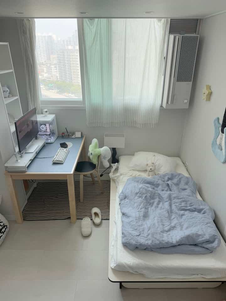 ホワイトとブルーの色調の6畳寝室、パソコンデスクとベッドが整然と配置されたナチュラルモダンなインテリア