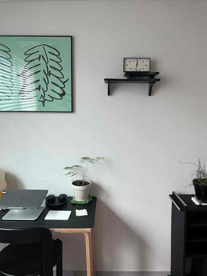 黒と白のトーンのシンプルなホームオフィス空間、デスク上にノートパソコンと植物が配置された雰囲気のある部屋