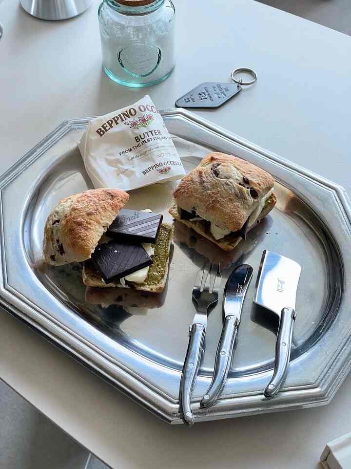 Silver metal tray on kitchen table featuring two small bread pieces with butter and chocolate, displaying a cozy snack setup