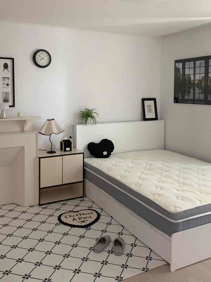 White and gray toned bedroom featuring a mattress, nightstand, and modern posters creating a clean atmosphere