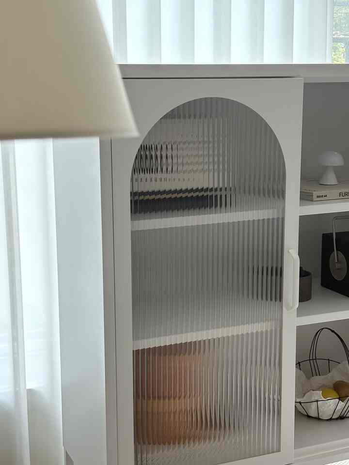 Minimal and natural space featuring a bright white and wood tone storage shelf, cream white chiffon curtain, and floor lamp