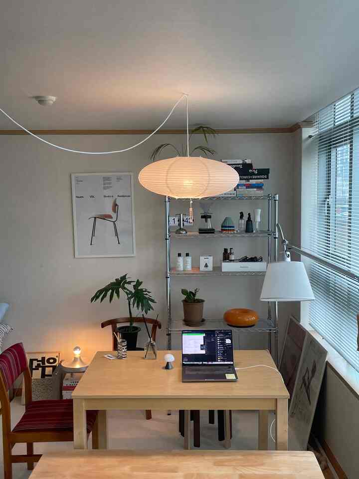 白い壁と木目調のダイニングテーブルが配置されたナチュラルな二人用ダイニングルームのホームオフィス風インテリア