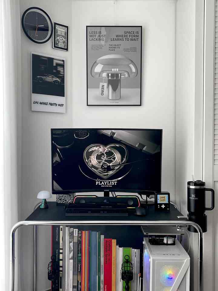 Modern black and white toned compact home office game room featuring gaming monitor, desk, and RGB LED soundbar