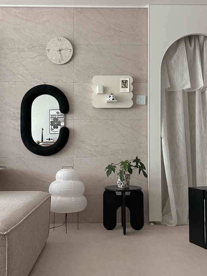 ベージュトーンの壁と床に黒いスツールと植物が配置されたモノトーンのリビング、自然でミニマルな雰囲気のインテリア