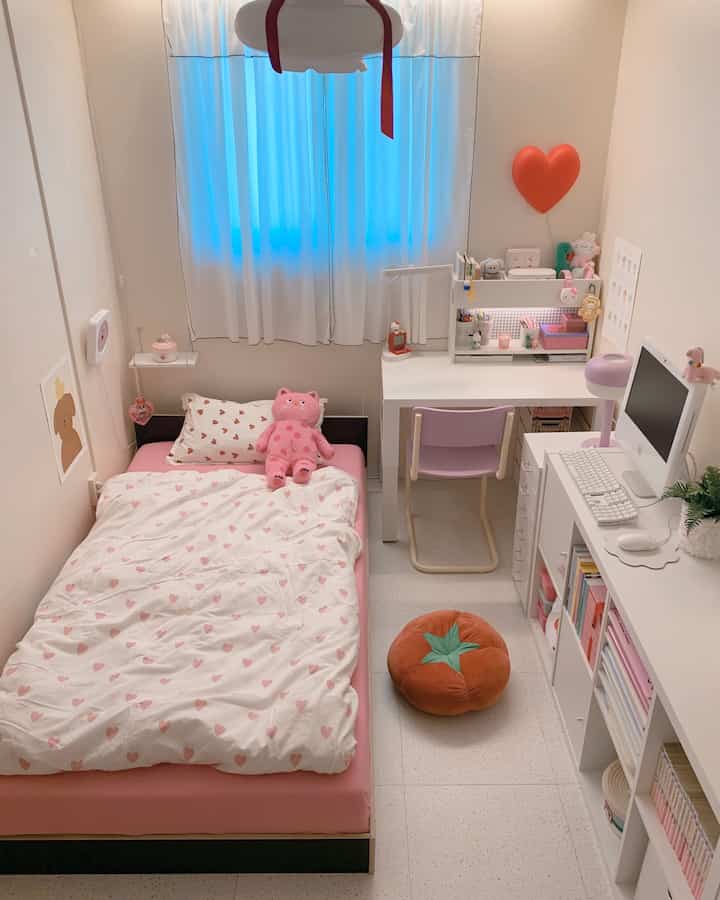 白とピンクの色調の子供部屋、ピンクのベッドとデスク、壁照明が配置された雰囲気のある空間