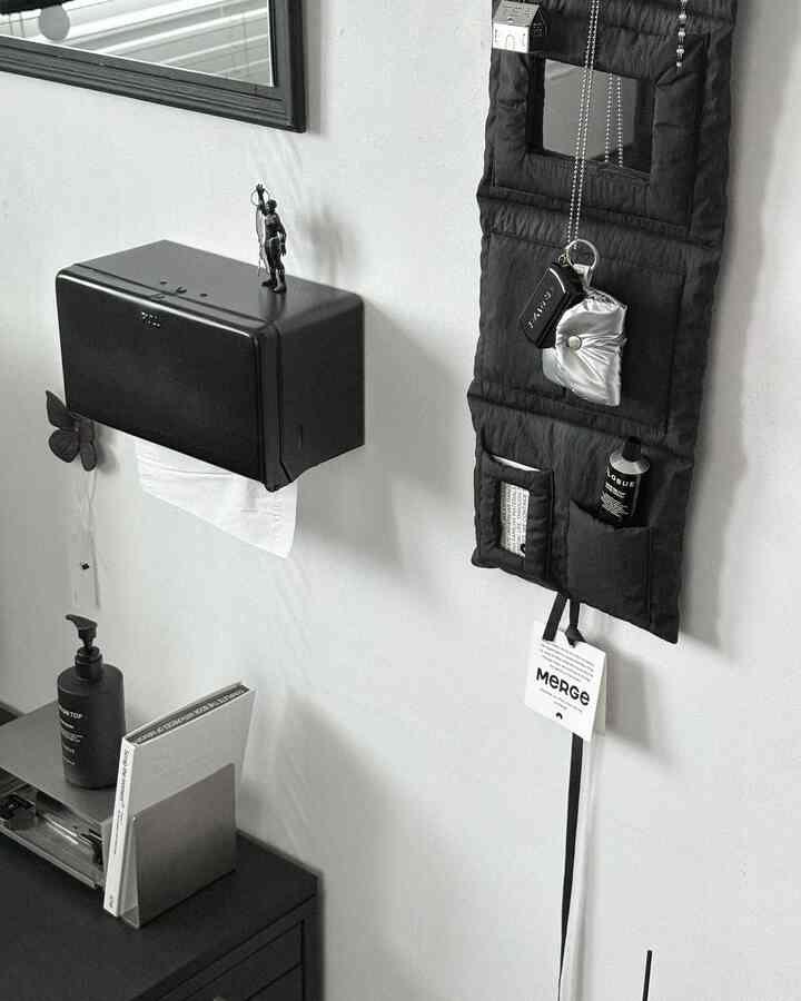 黒と白のトーンの玄関、壁に掛けられた収納ポケットとティッシュケースが配置されたシンプルで清潔感のある空間