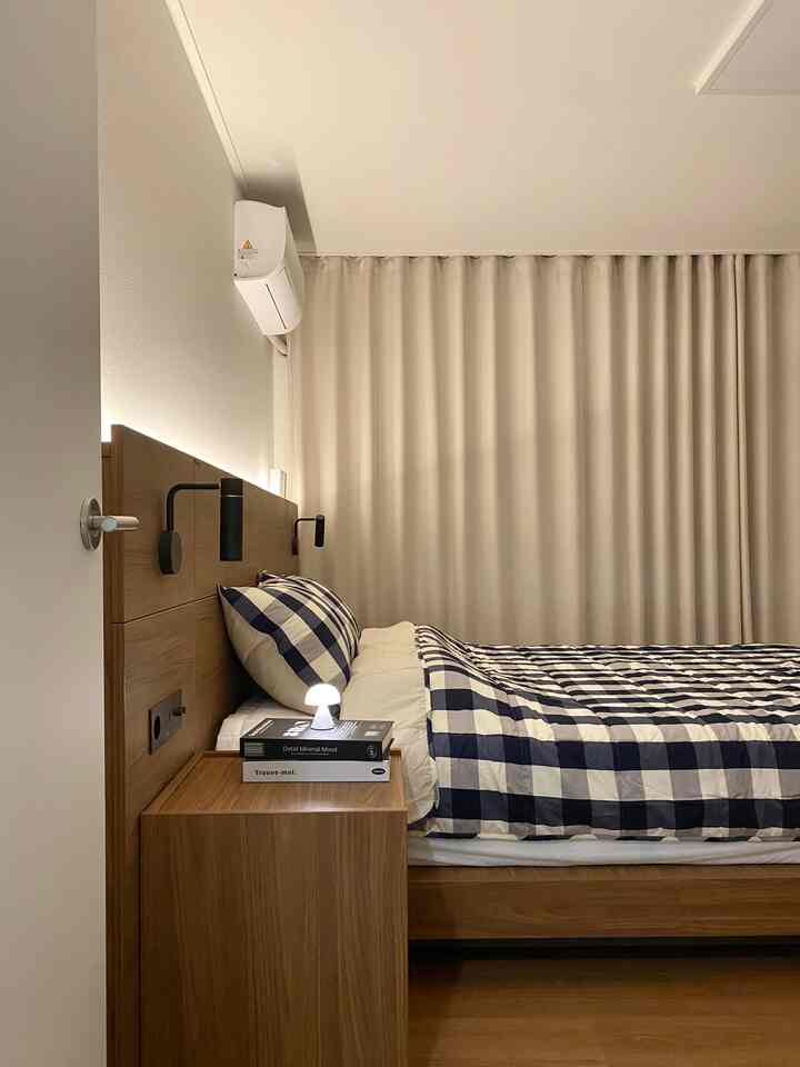 ベージュ色調の寝室、クラシックなネイビーの大きなギンガムチェック柄サマーキルトセットが配置された印象的な空間