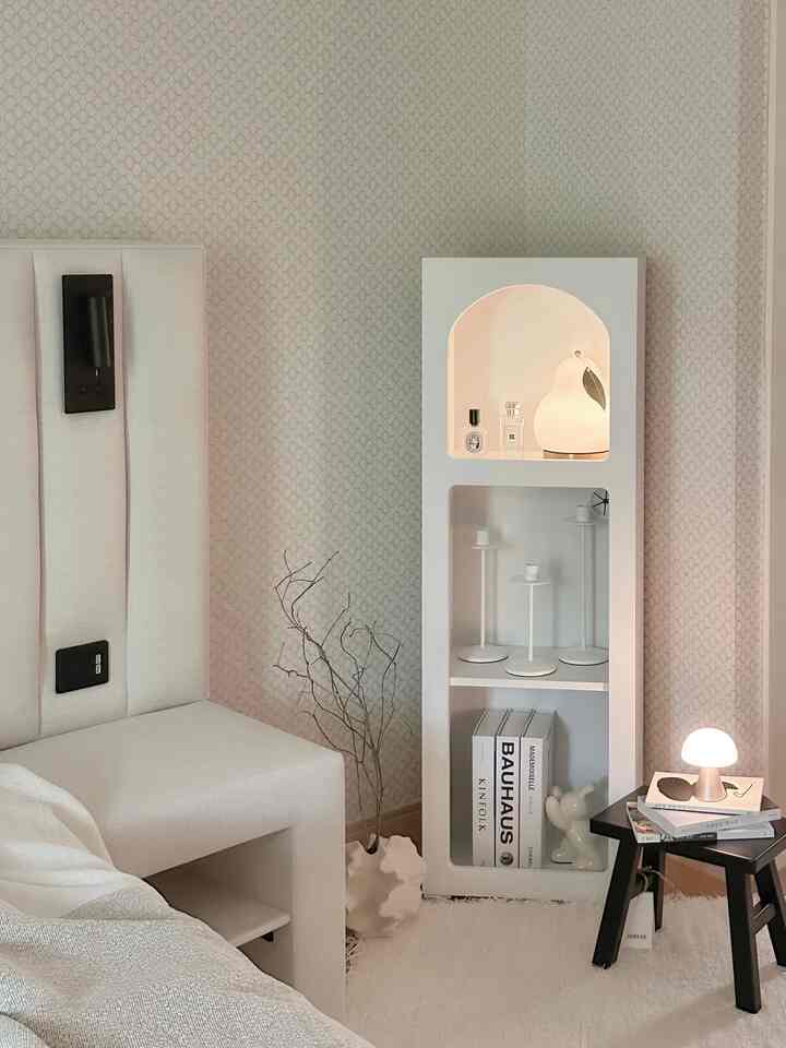 White and beige toned bedroom corner featuring a Dalia cabinet and a small nightstand with table lamp creating a cozy atmosphere