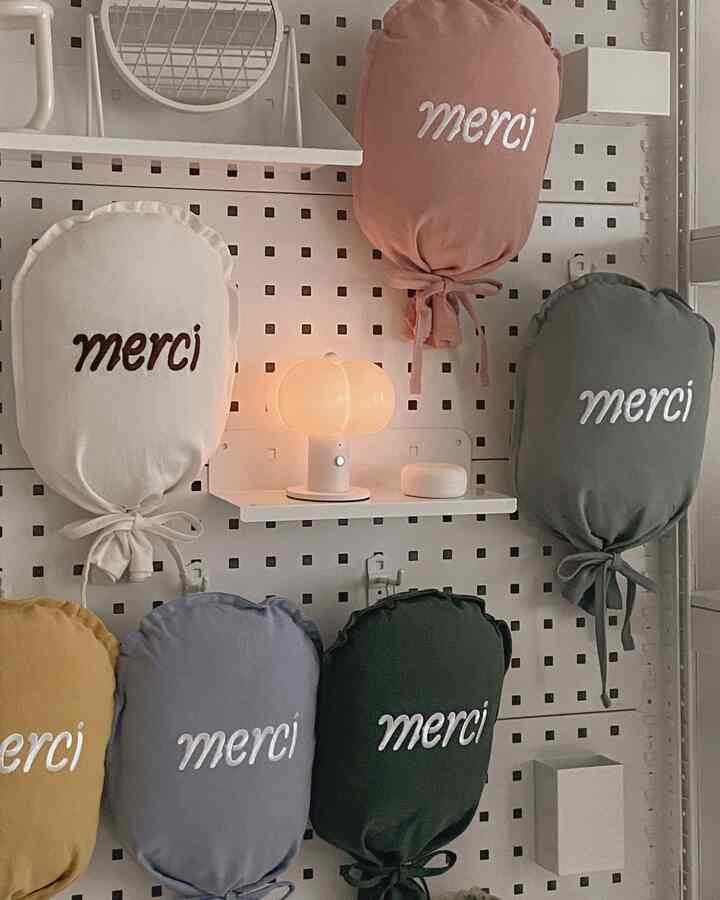 白い有孔ボードの壁に多彩なクッションとミニランプが配置された雰囲気のある収納スペース