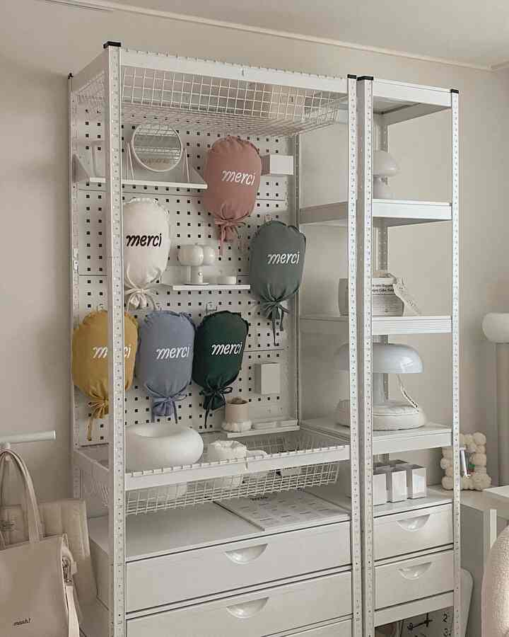 白を基調としたウォークインクローゼット、マルチ収納棚とカラフルなクッションが整然と配置された印象的な空間