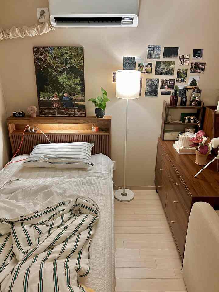 白とベージュのトーンのワンルーム寝室、木製家具と白のフロアランプ、壁飾りが配置された雰囲気のあるインテリア