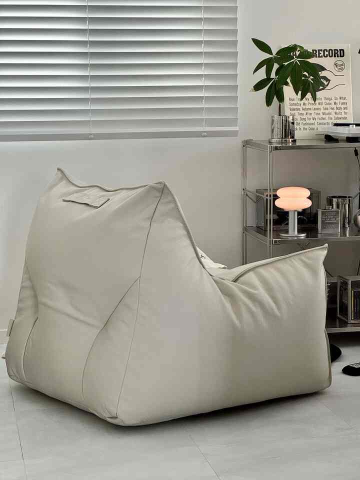 Natural modern living space with large beige bean bag sofa and silver metal shelf, creating a light and cozy tone