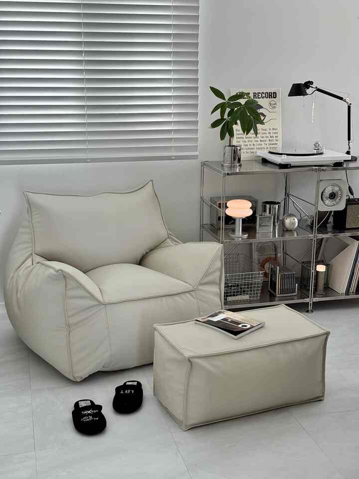 A modern study with white and beige tones featuring a premium leather bean bag sofa, ottoman, and a turntable for a cozy relaxation space