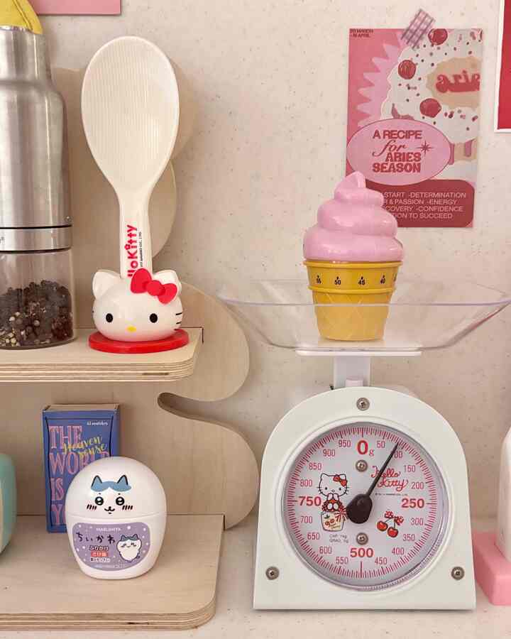 White and pink toned cozy kitchen space featuring Hello Kitty themed utensils and scale placed on a compact shelf
