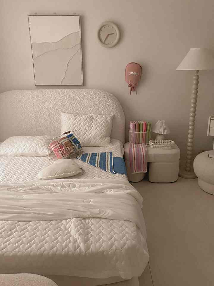 オートミール色調のシンプルな寝室、ハート模様の寝具とカラフルなタオルが配置された雰囲気のあるインテリア