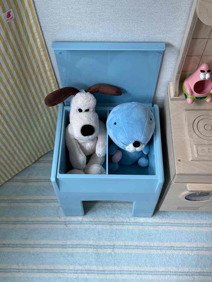 青いスツール型収納と木製のキッチン玩具が配置された子供部屋、柔らかな色調で温かみのある雰囲気のインテリア