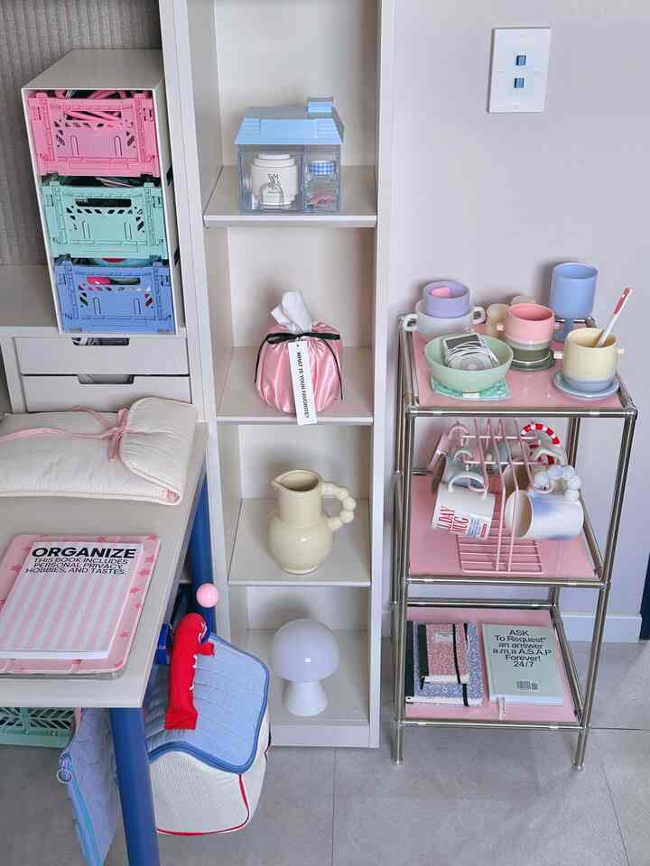 パステルカラーのコンパクトな空間、棚やテーブルにカップや本などが整然と配置された雰囲気のあるインテリア