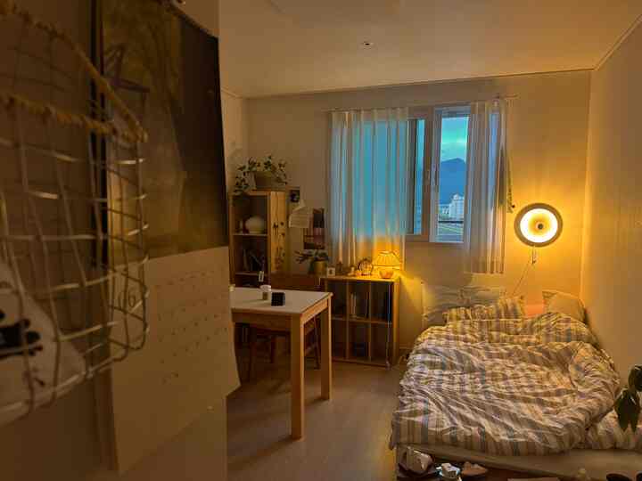 暖かい木目調と黄色い照明が特徴の4.5畳寝室、本棚とカーテンが配置された居心地の良い空間